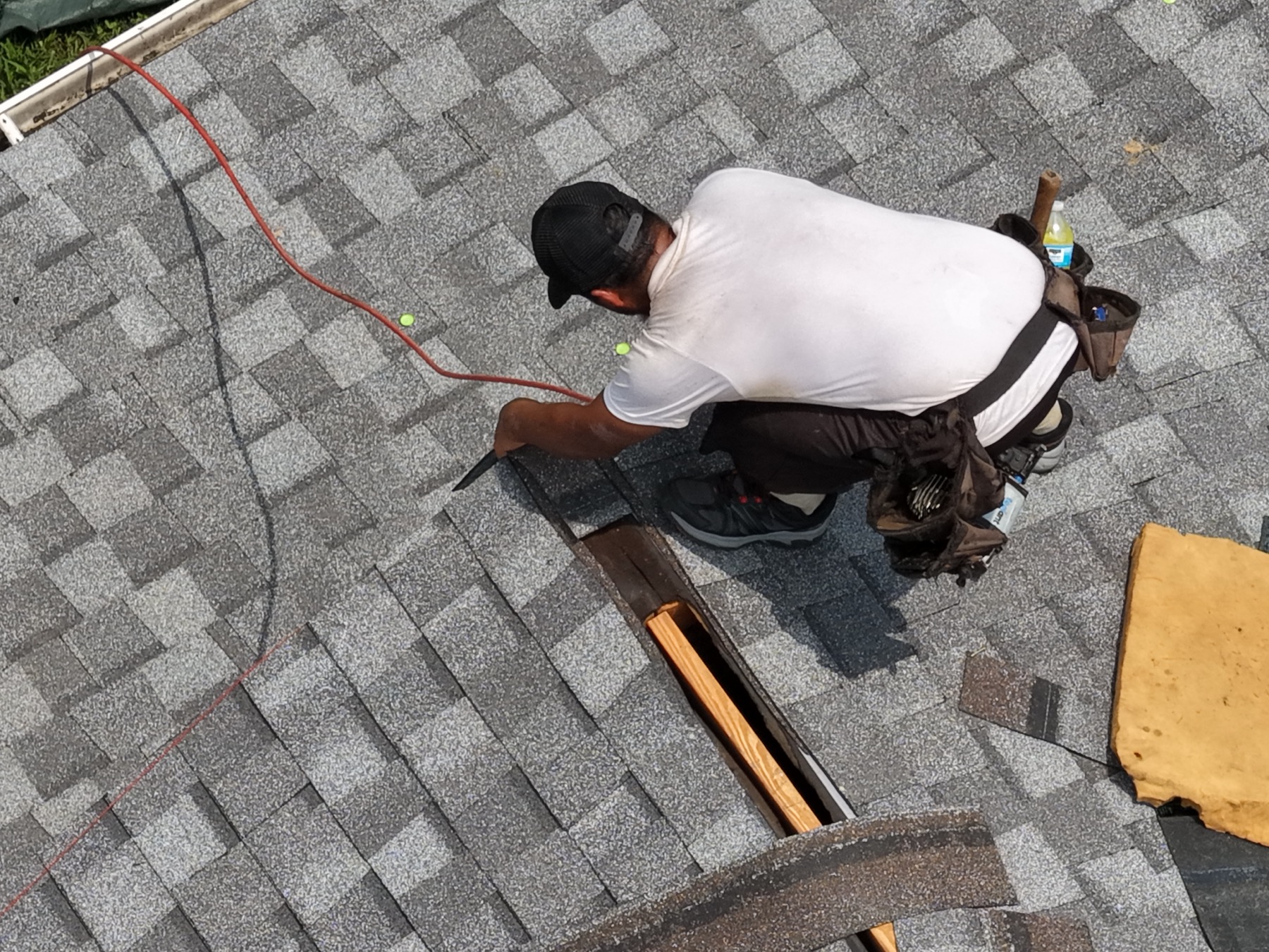 A roofer installing the finishing ridge shingles